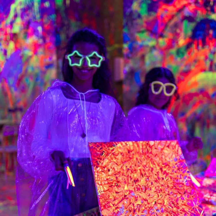 Girls with star glasses holding a glowing canvas