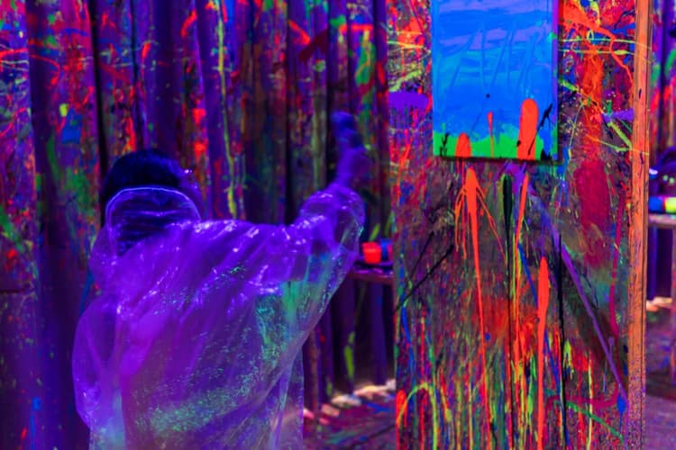 Kid splatting neon paint at a canvas